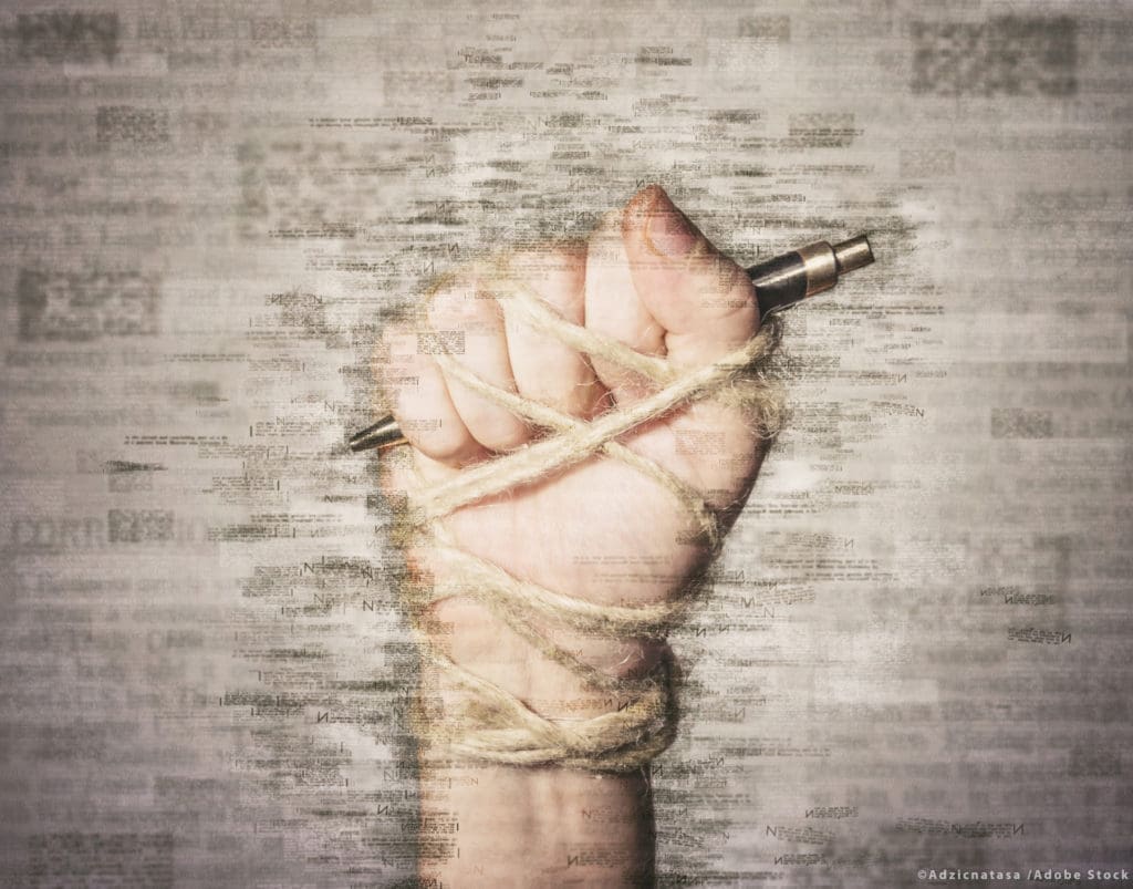 Hand with pen tied with rope, depicting the idea of freedom of t